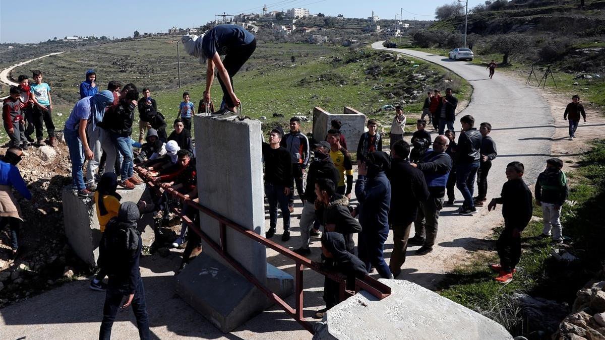 Jóvenes palestinos retiran una barrera de la entrada del pueblo de Aboud, en la Cisjordania ocupada por Israel.