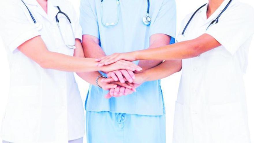 Tres sanitarios unen sus manos.