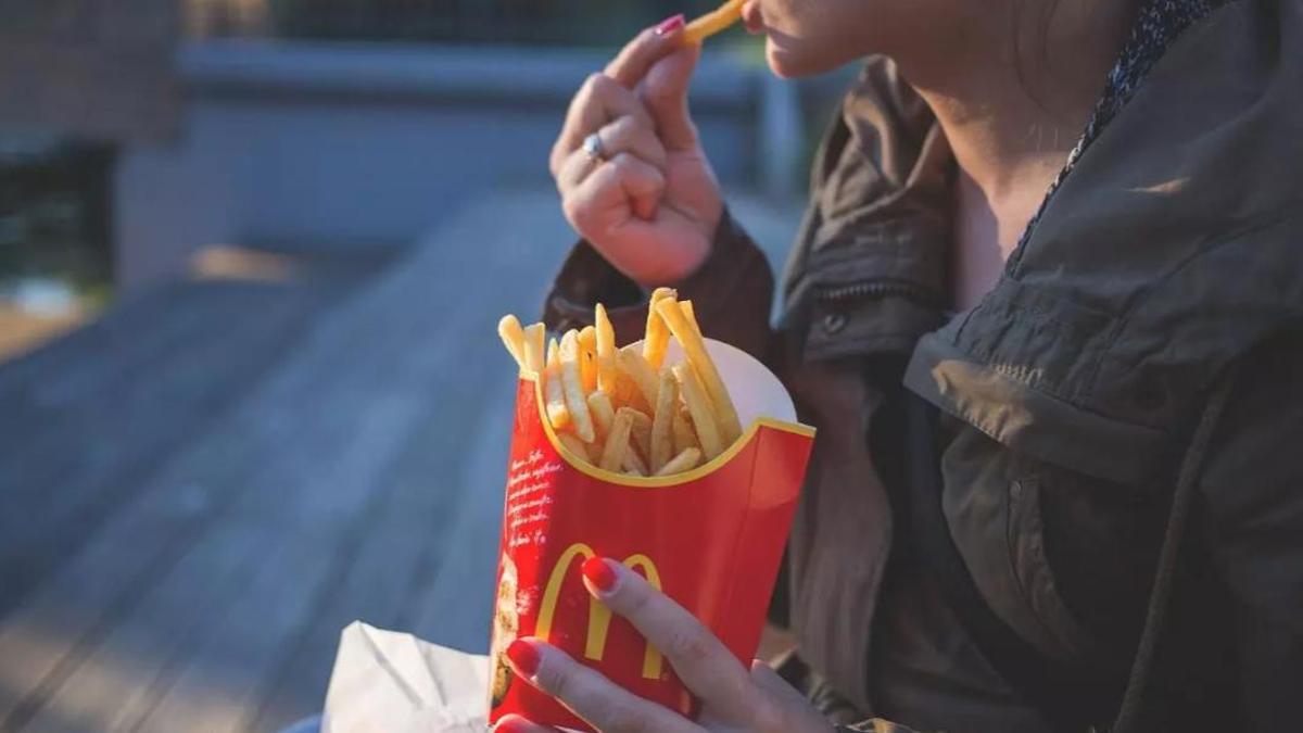 Una persona menja patates fregides de McDonald's