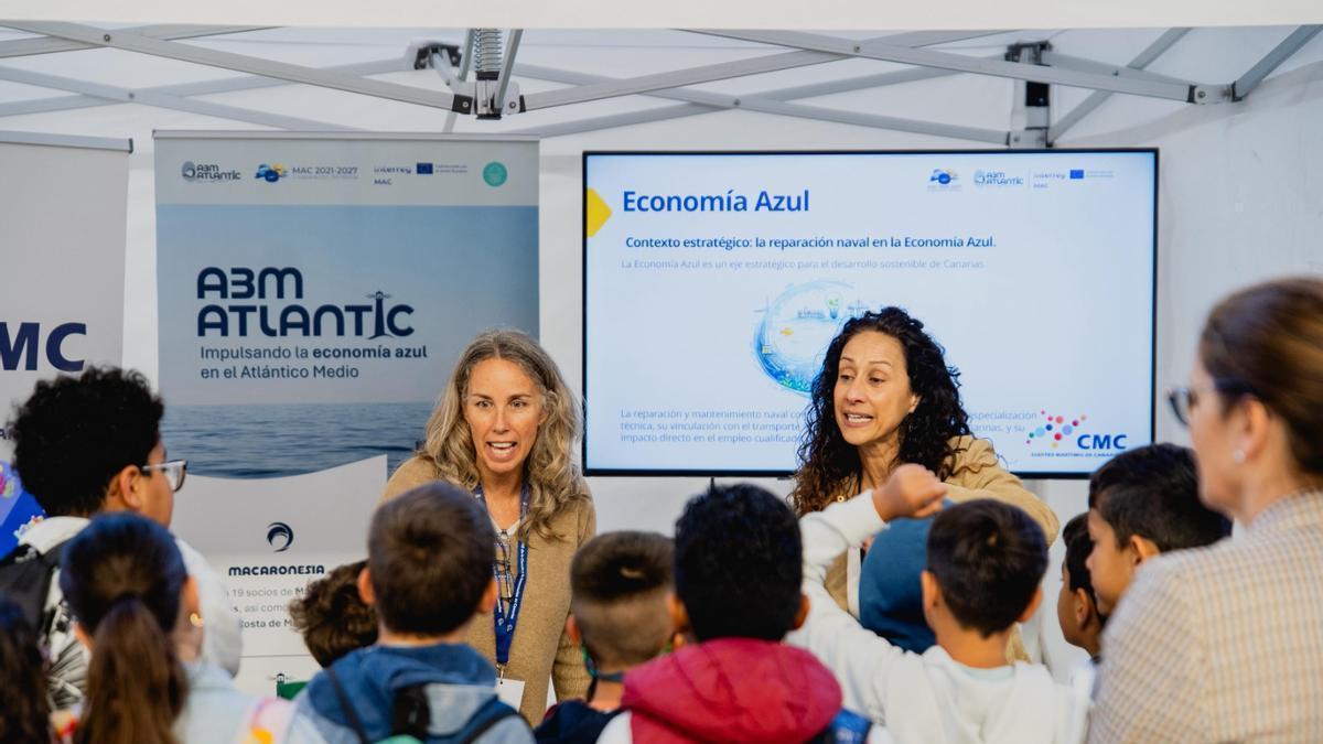 Unas guías se dirigen a un grupo de alumnos que visitó la feria.