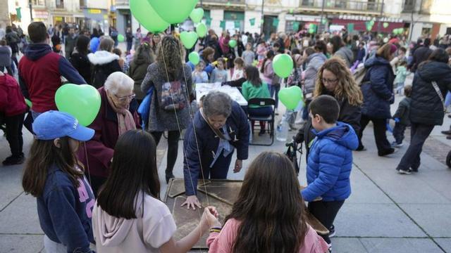 A la izquierda, la plaza de la Constitución llena de asistentes y sobre estas líneas, menores en la actividad del pintacaras. | J. L. FERNÁNDEZ