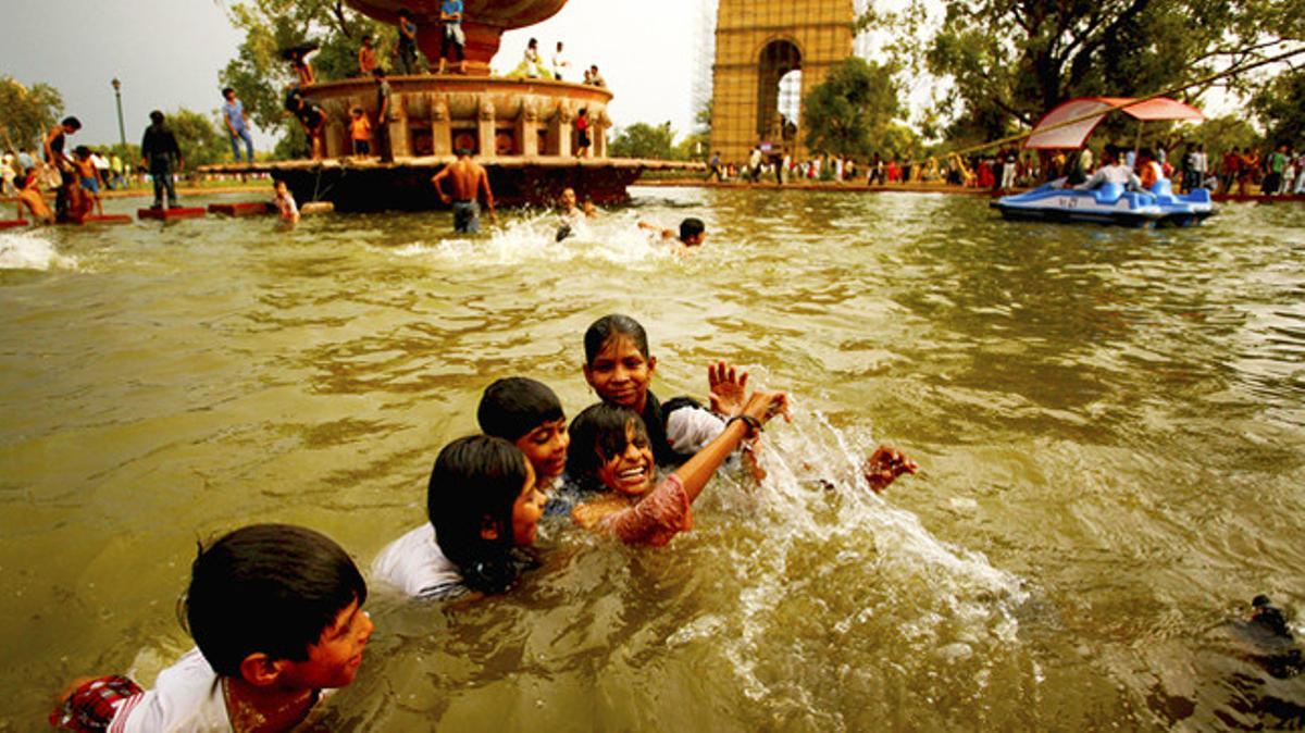 Nens jugant a prop de la Porta de l’Índia, monument als caiguts durant la guerra, després de la pluja a Nova Delhi.