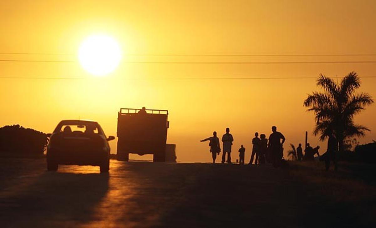 Algunes persones esperen un transport al costat d’una carretera, a San Cristóbal (Cuba), mentre que el govern de l’illa comença el pla de reajustament per reduir la plantilla estatal.