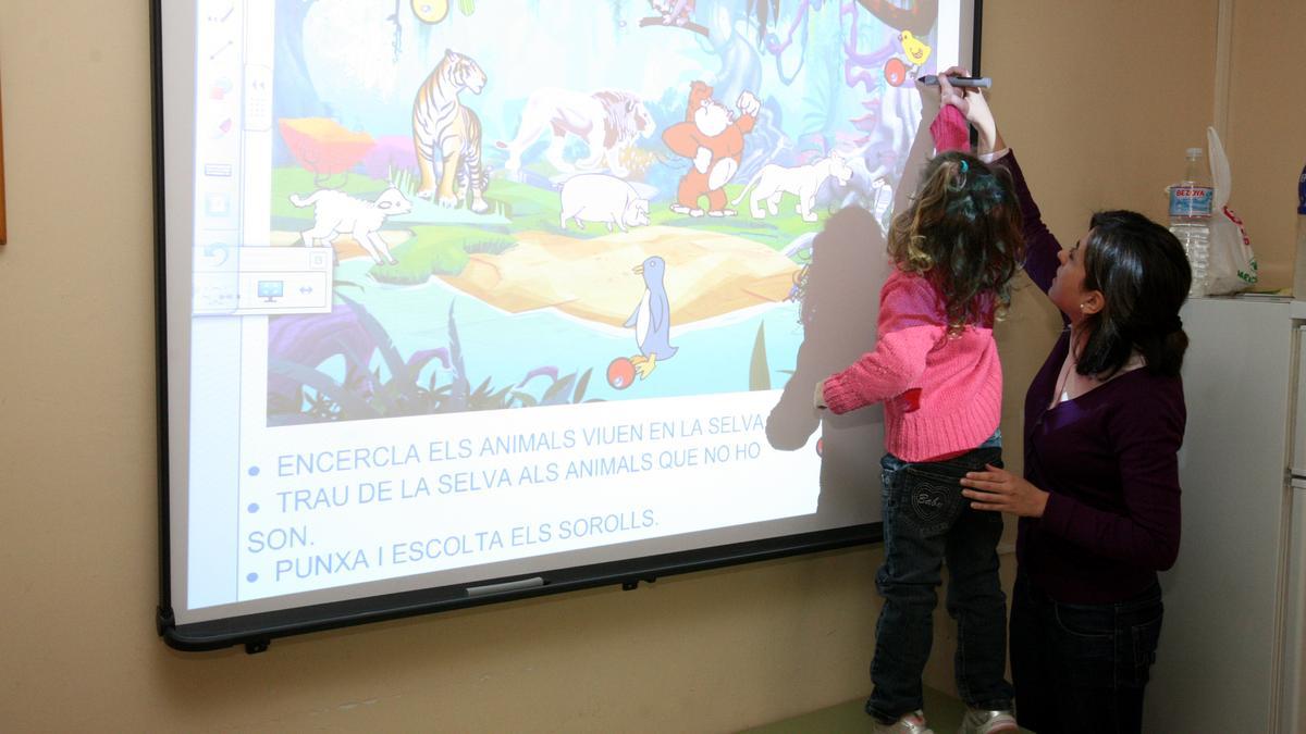 Una profesora y una alumna utilizan una pizarra interactiva durante una clase.