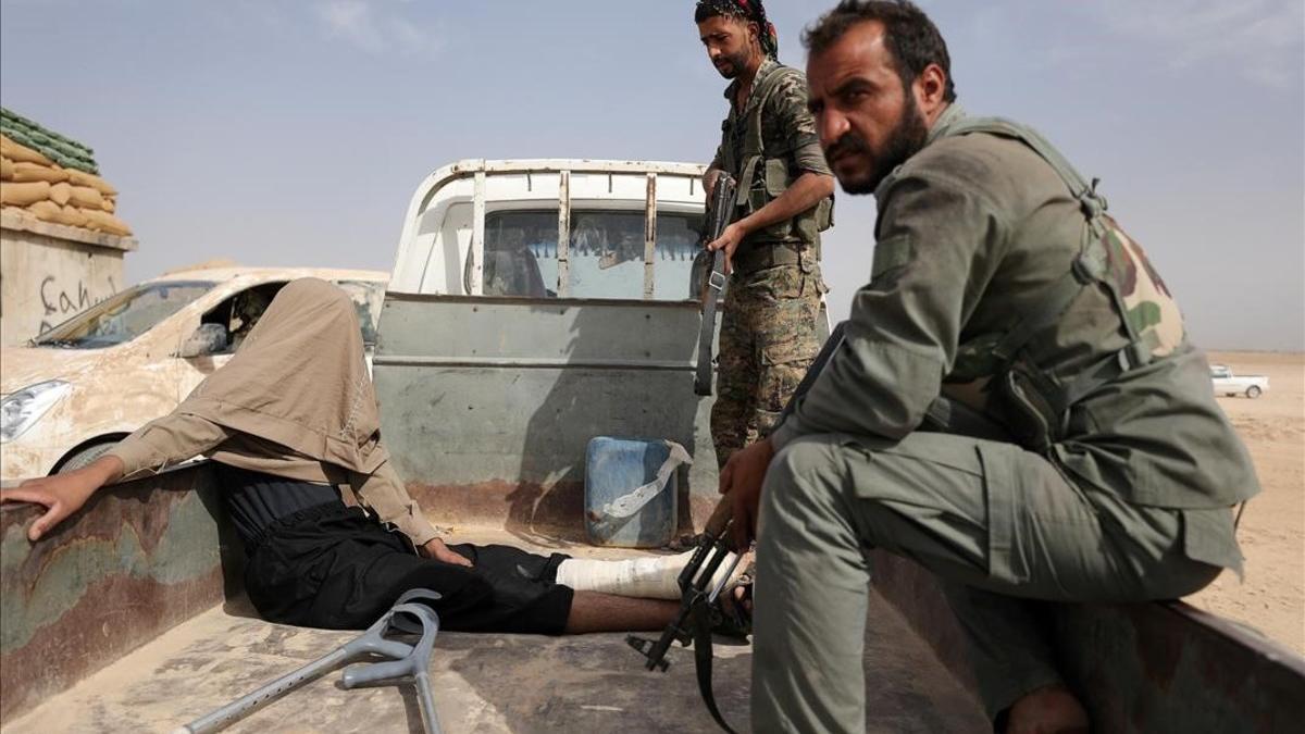 Combatientes de las Fuerzas Democráticas de Siria tras arrestar a un hombre herido durante su combate con el Estado Islámico en la zona norte de Deir al-Zor, en Siria.