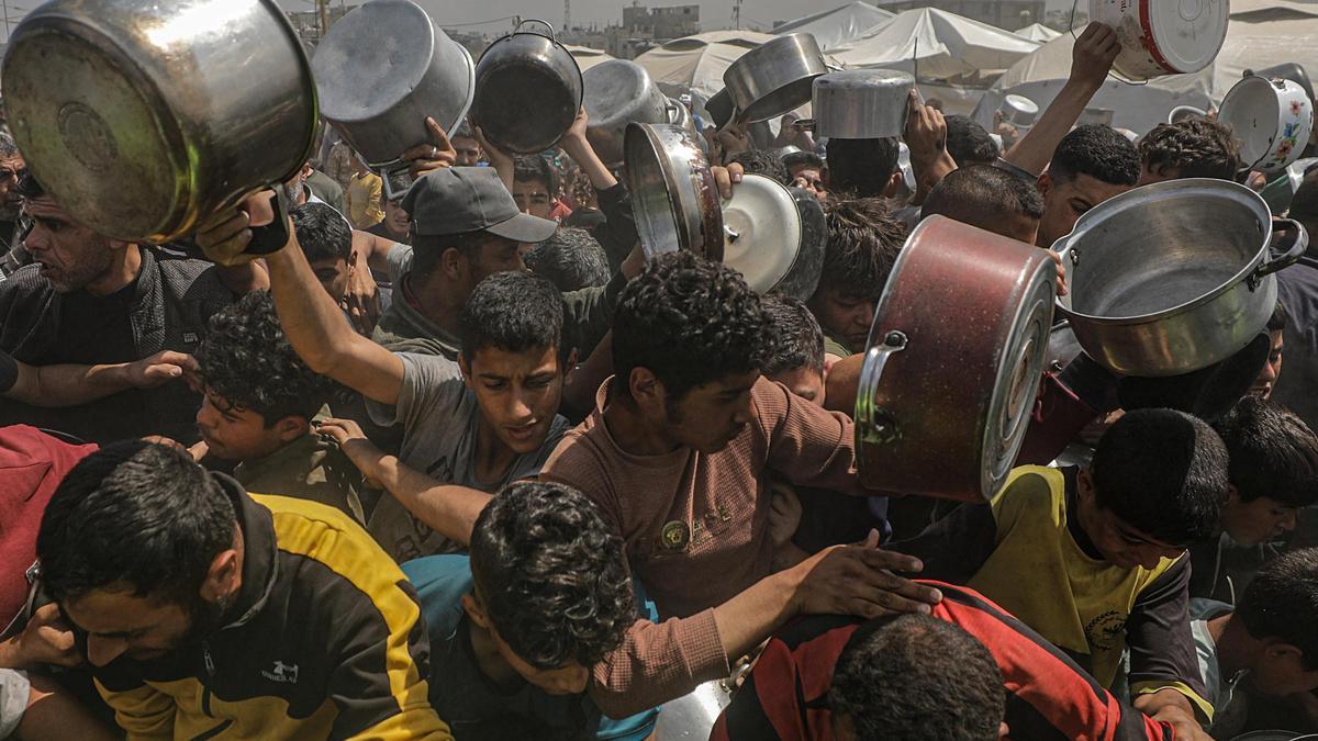 Gazatíes desplazados hacen cola para recibir una ración de comida en en campo de refugiados de Jabalia, en el norte de la Franja.