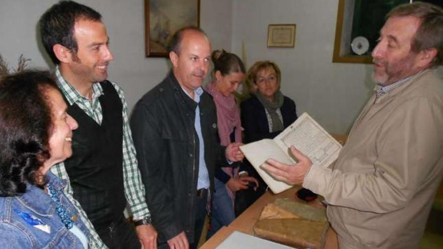 Rafael Sánchez (a la derecha), muestra los antiguos documentos ante la bibliotecaria, alcalde y ediles.  // E.G.