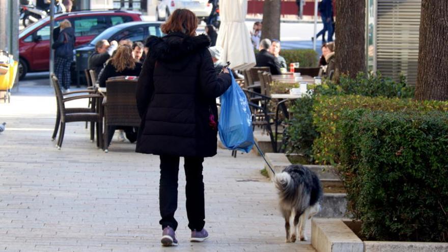 Una dona passejant un gos pel centre de Girona