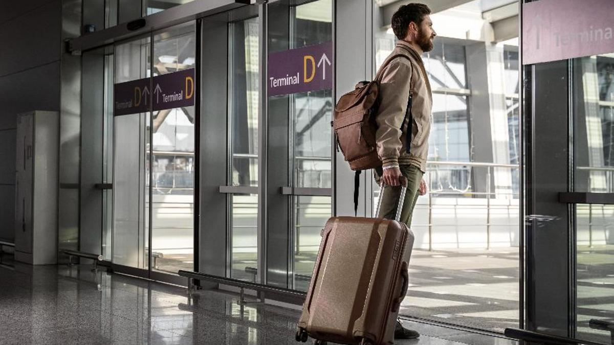Un home amb una motxilla i una maleta a l'aeroport