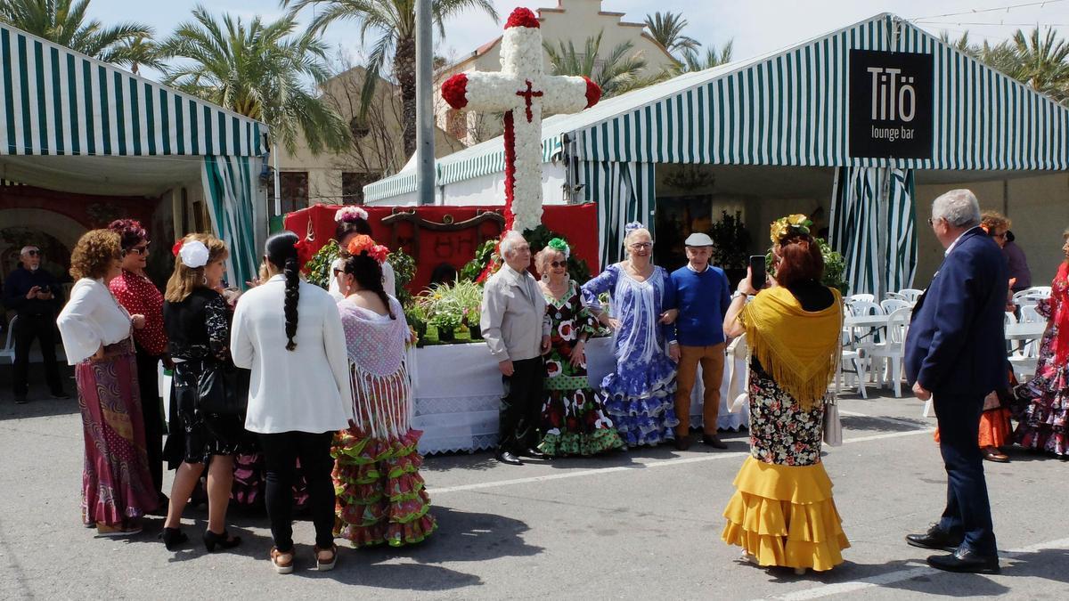Miembros de la Casa de Andalucía vestidos de sevillana junto a algunas carpas como la de un pub de la ciudad