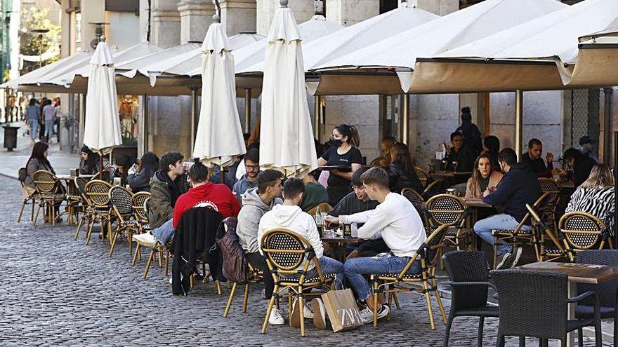 Gent asseguda a una terrassa de la plaça de la Independència.