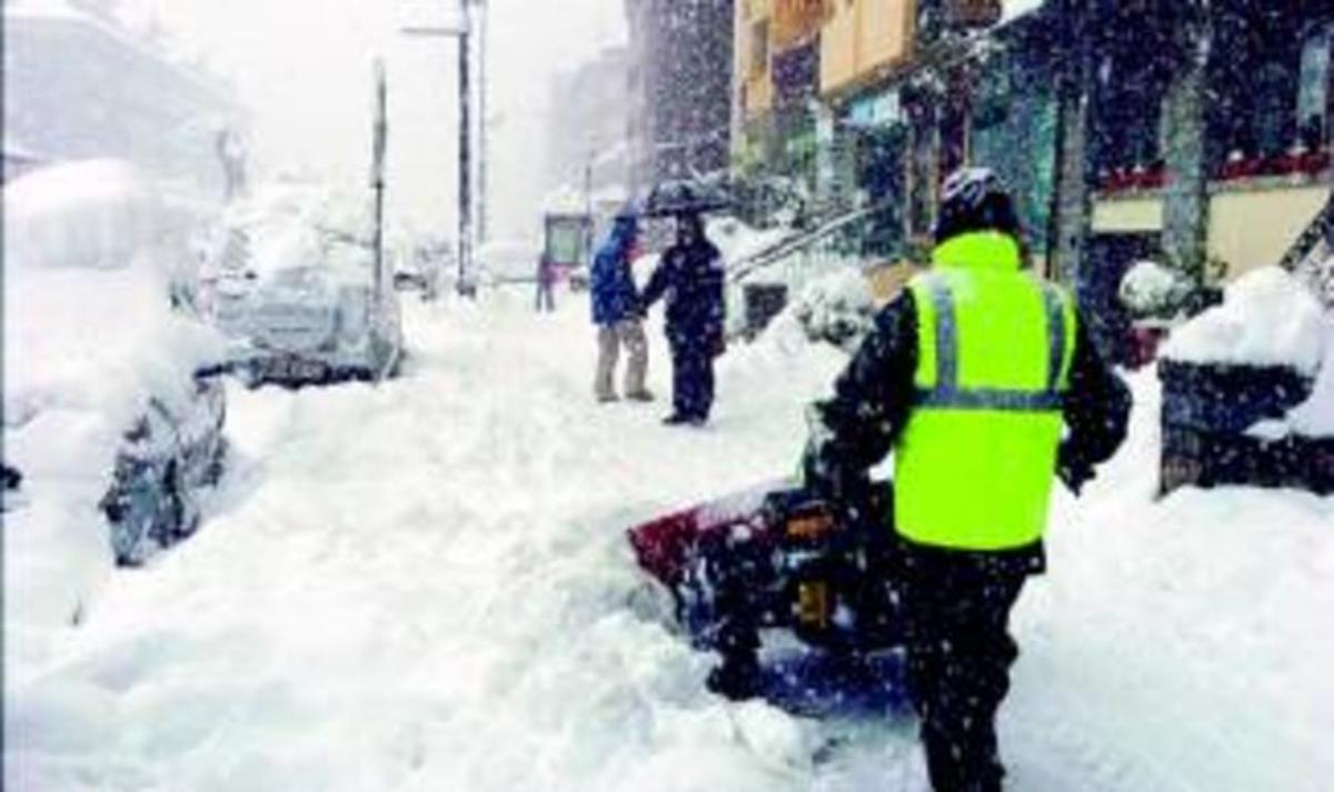 Un home retira neu de la vorera d’un carrer del centre de Viella, ahir.