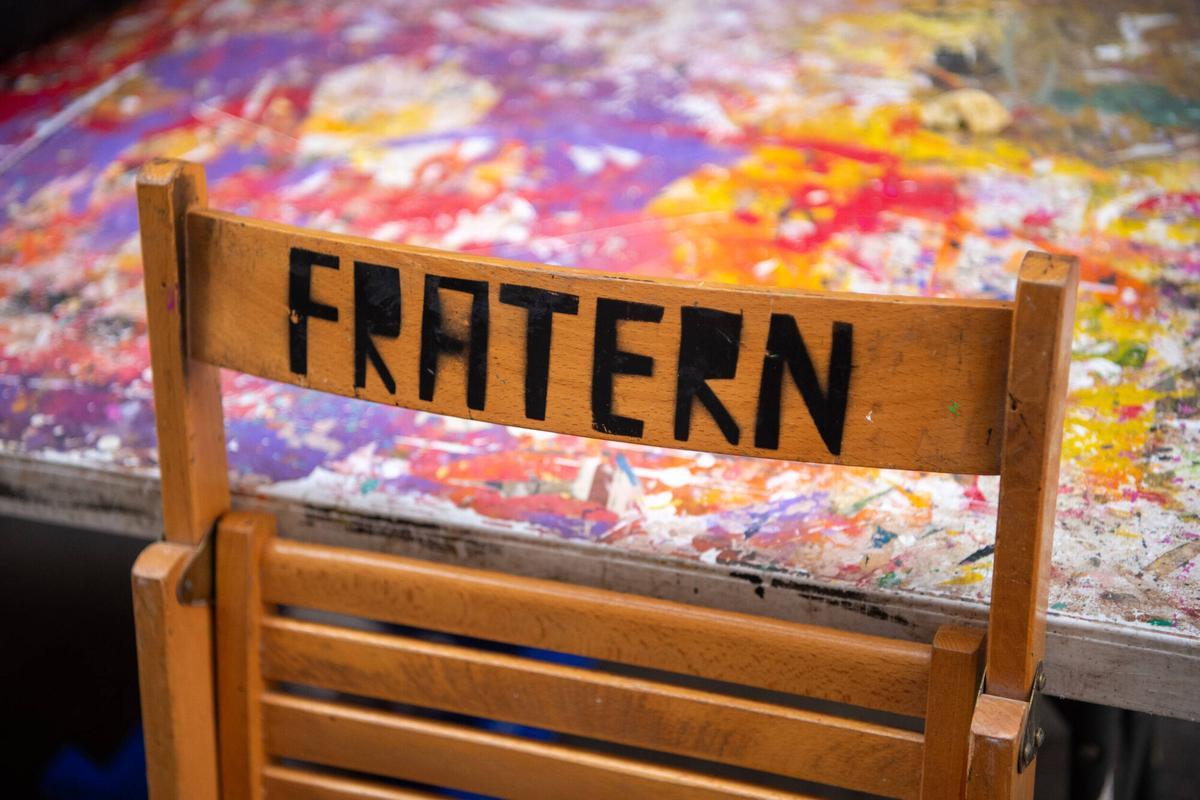 Una silla de madera de la comisión de fiestas de la calle Fraternitat de Dalt, sobre una mesa manchada de pintura donde hacen los preparativos para las próximas fiestas mayores de Gràcia. Barcelona, 4 de agosto de 2026. Foto: Belén González / EP