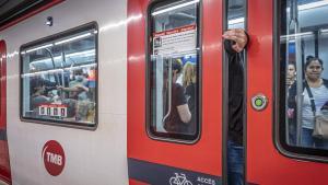 Un pasajero saca la mano por la puerta de un tren del metro de Barcelona a punto de arrancar.