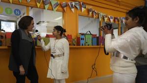 La pequeña Gursimar graba con la cámara mientras su compañera Asima entrevista a la alcaldesa, Ada Colau, este viernes en el Institut Escola Trinitat Nova.