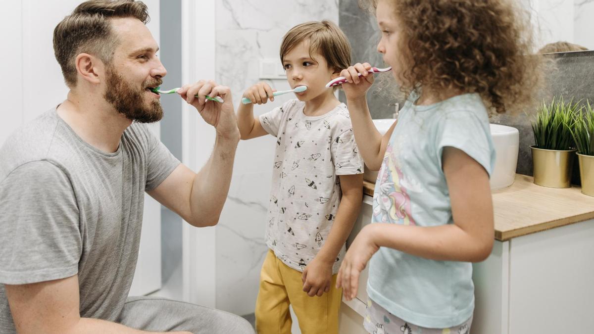 Un padre se lava los dientes con sus hijos.