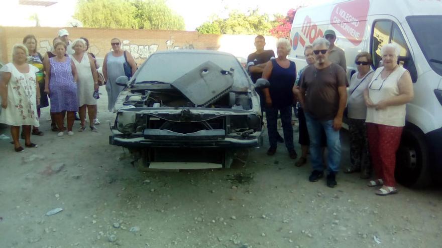 Vecinos de los bloques próximos al descampado, este lunes junto a los restos de uno de los coches abandonados, que se usa para dormir.