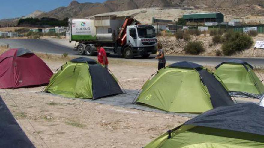 Un camión de basuras pasa junto al campamento instalado frente al vertedero.