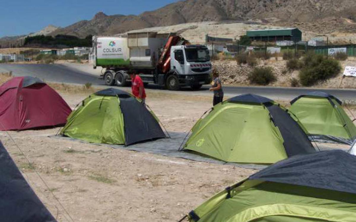 Un camión de basuras pasa junto al campamento instalado frente al vertedero.