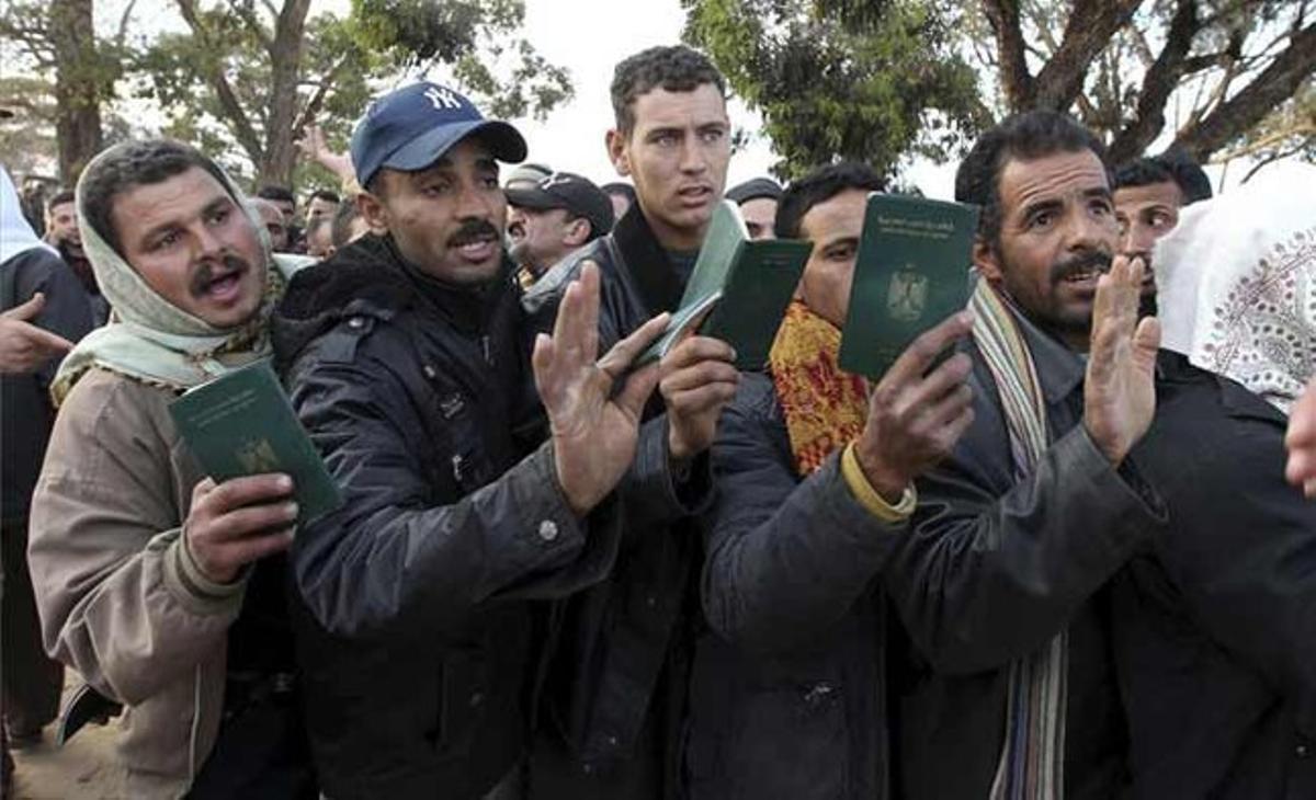 Refugiats provinents de Líbia mostren els seus passaports mentre fan cua per travessar la frontera. Refugiats provinents de Líbia mostren els seus passaports mentre fan cua per travessar la frontera.