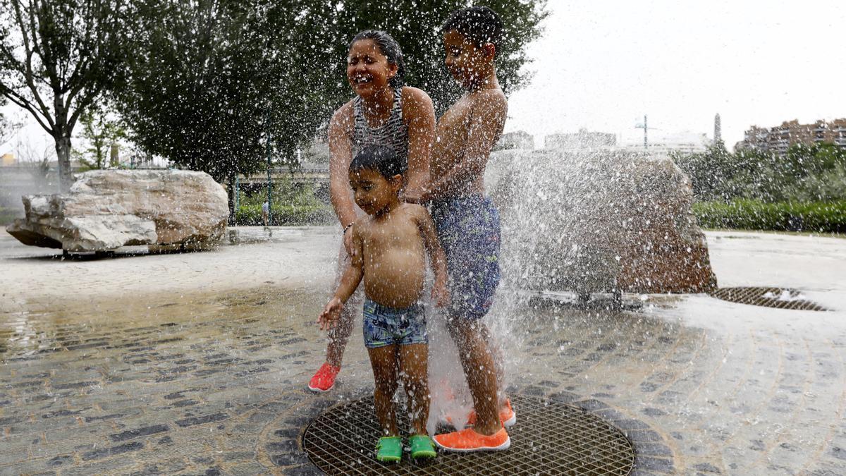 Varios jóvenes juegan con el agua en la zona de la Expo