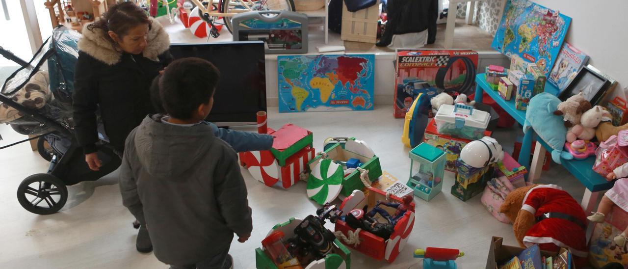 Un niño contempla juguetes de segunda mano en el mercadillo de Carabelo.