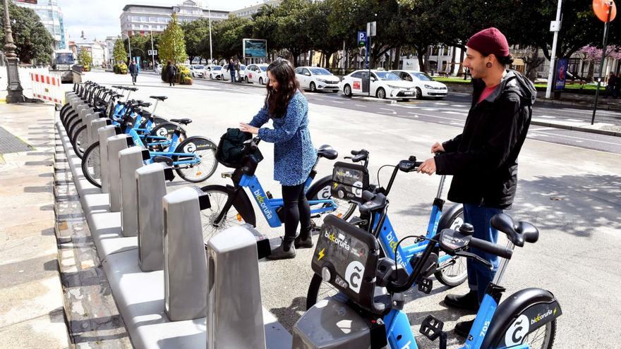 Dos jóvenes retiran bicicletas de la estación de BiciCoruña del Cantón Grande.