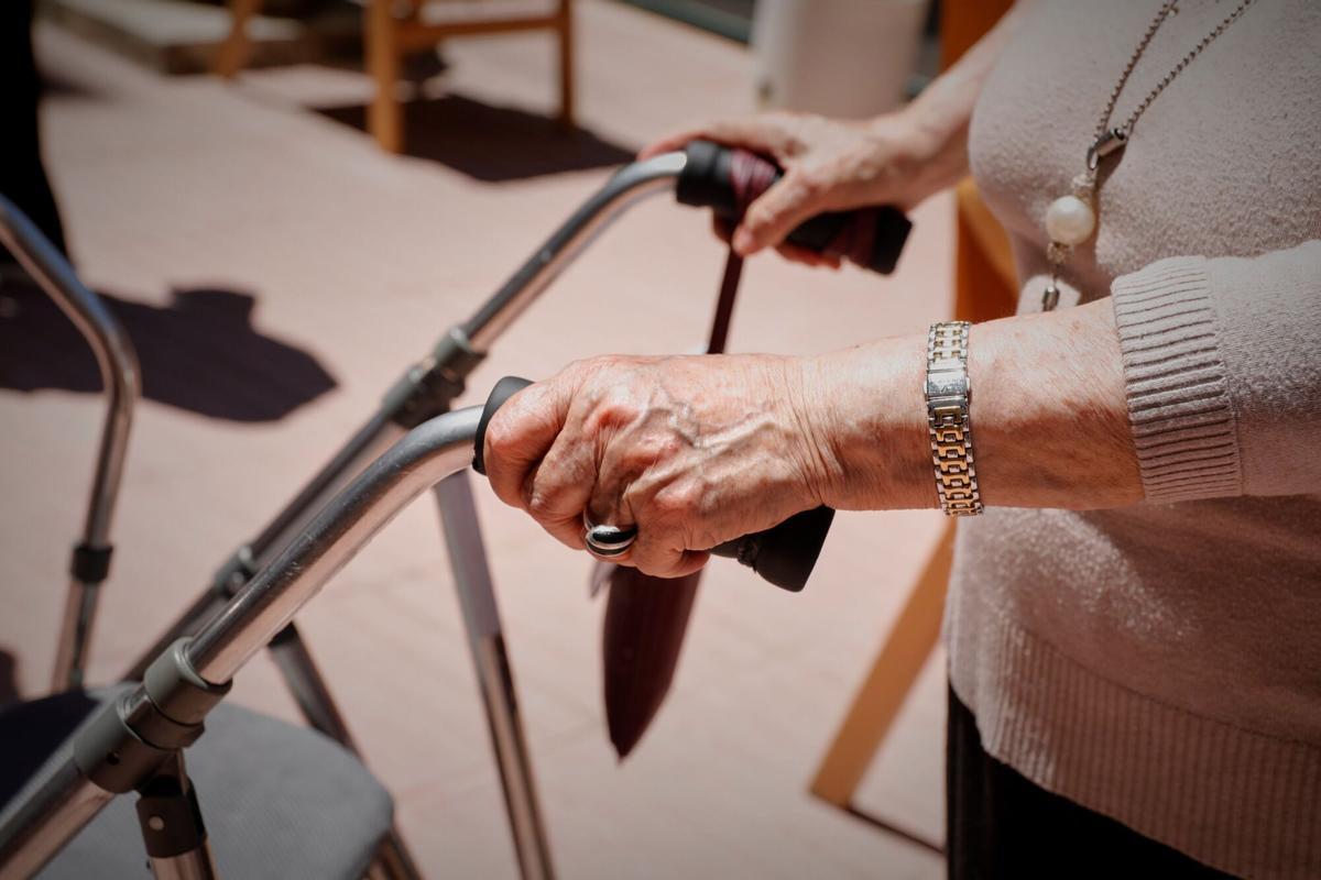 Una anciana sujeta su andador en una residencia.