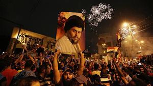 Un seguidor de Moqtada al Sadr sostiene una foto del clérigo en una concentración en la plaza Tahrir de Bagdad para celebrar el resultado electoral.