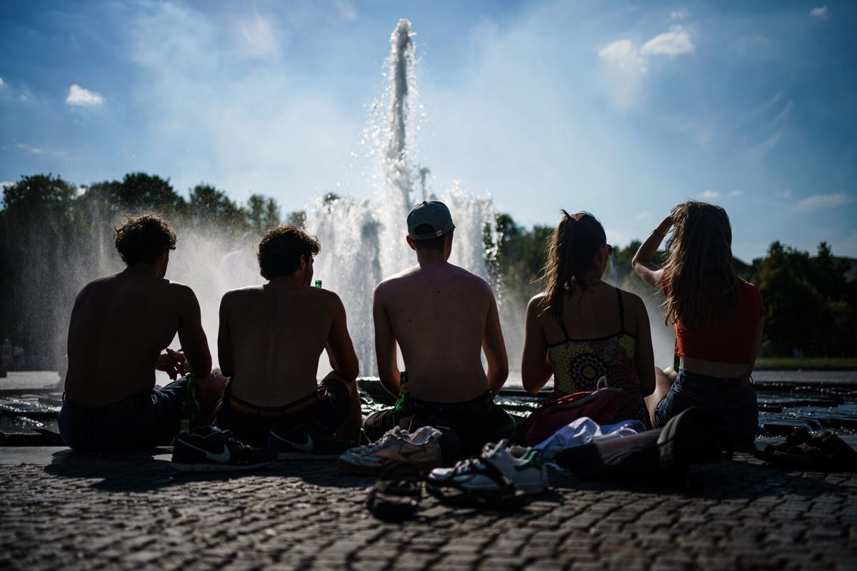 Unos turistas se refrescan en un parque de Berlín durante una ola de calor.
