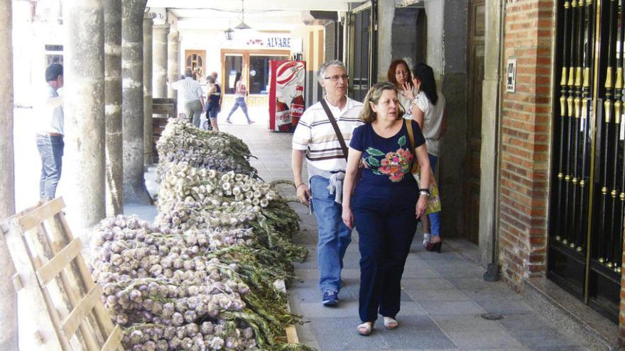 Vecinos pasean junto a un puesto de ajos situado en la plaza de Santa Marina. Foto