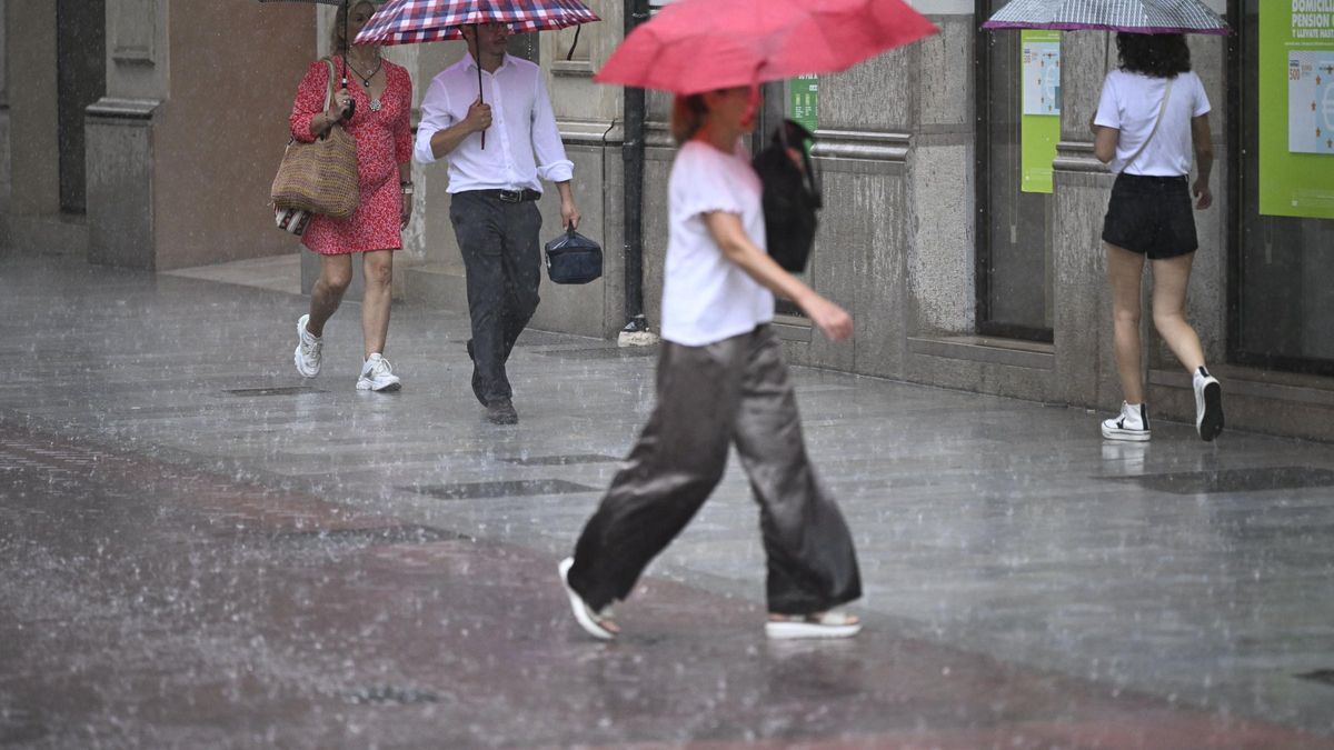 Varias personas caminan bajo una intensa lluvia.