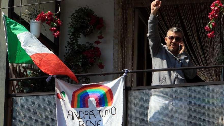 Un hombre saluda levanta el puño desde su balcón en Milán. // Efe