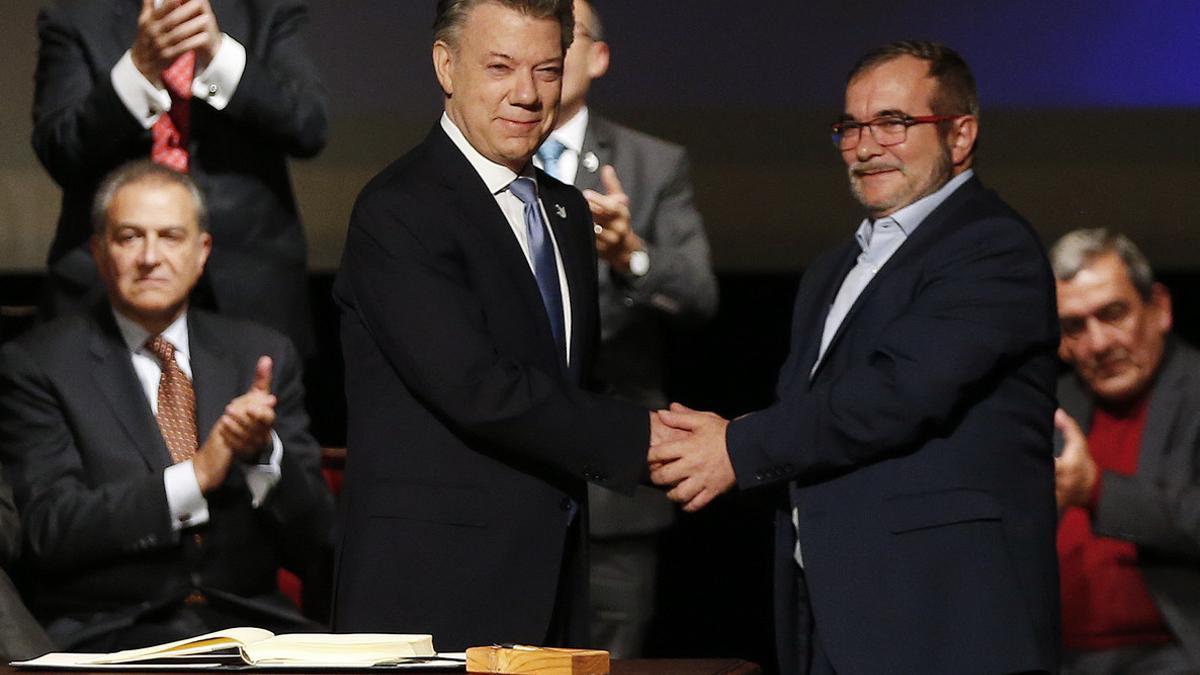 Santos (izquierda) y Rodrigo Londoño, alias 'Timochenko', se dan la mano tras firmar el nuevo acuerdo, en Bogotá, este jueves.