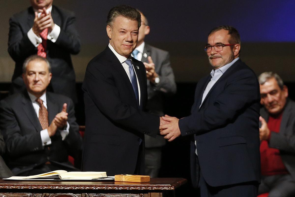 Colombia’s President Juan Manuel Santos, left, shakes hands with Rodrigo Londono, known as Timochenko, top leader of the Revolutionary Armed Forces of Colombia, FARC, after signing a revised peace pact at Colon Theater in Bogota, Colombia, Thursday, Nov. 24, 2016. An original accord ending the half century conflict was rejected by voters in a referendum last month. (AP Photo/Fernando Vergara)