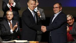 Colombia’s President Juan Manuel Santos, left, shakes hands with Rodrigo Londono, known as Timochenko, top leader of the Revolutionary Armed Forces of Colombia, FARC, after signing a revised peace pact at Colon Theater in Bogota, Colombia, Thursday, Nov. 24, 2016. An original accord ending the half century conflict was rejected by voters in a referendum last month. (AP Photo/Fernando Vergara)