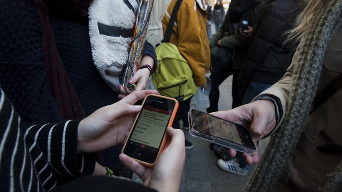 Unos jóvenes consultan sus teléfonos móviles en un instituto de Barcelona, el viernes.