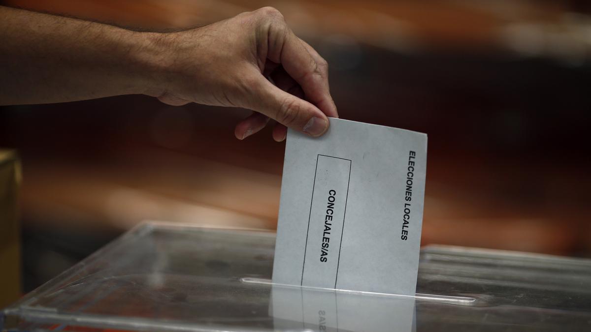 Foto de archivo de una persona depositando un sobre en el interior de una urna electoral.