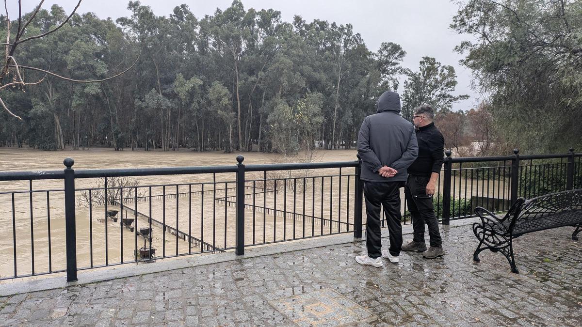 Dos vecinos observan la crecida del río Genil en Palma del Río durante las pasadas inundaciones.