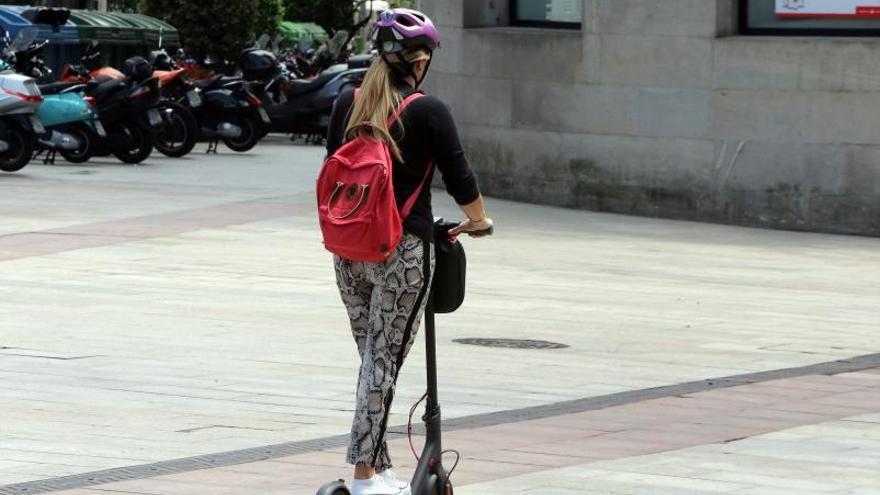 Una usuaria de patinete elécrico en una calle de Vigo