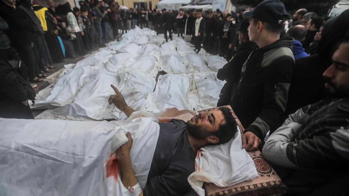 25 December 2023, Palestinian Territories, Deir Al-Balah: An injured Palestinian man is transported near the bodies of Palestinians who were killed after heavy Israeli bombardment of the Al-Maghazi camp in the central Gaza Strip, at the morgue of Al-Aqsa