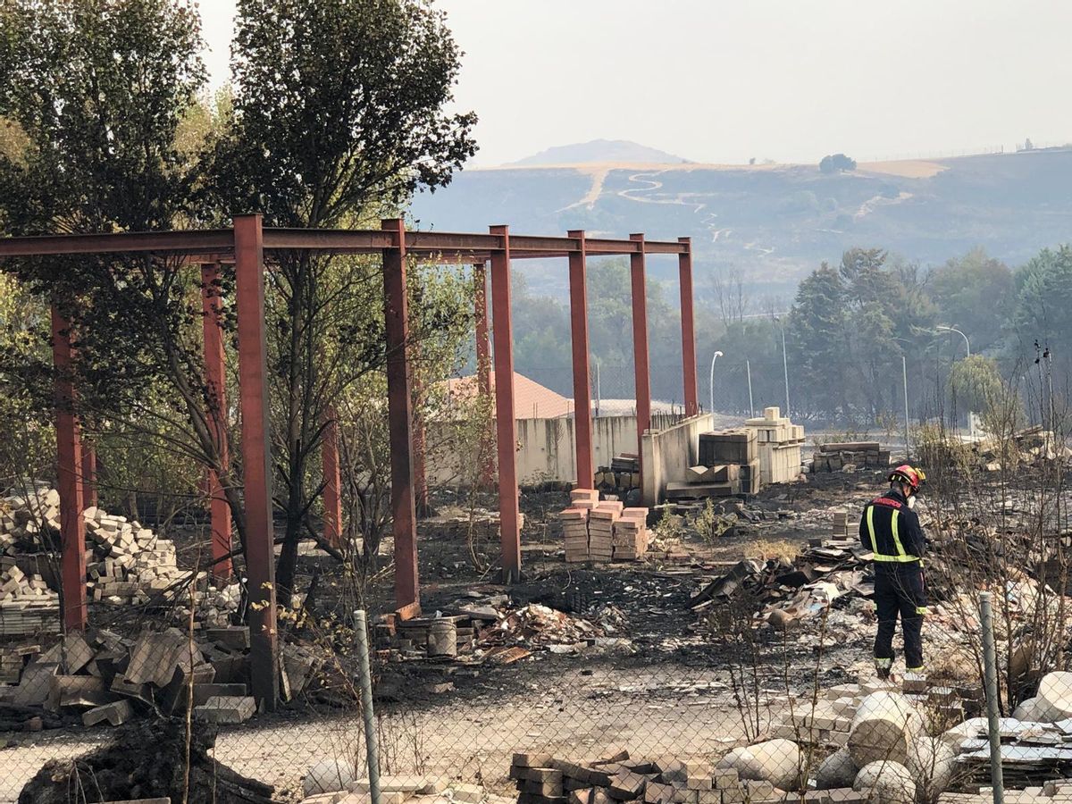 Un bombero descansa junto a una estructura calcinada.
