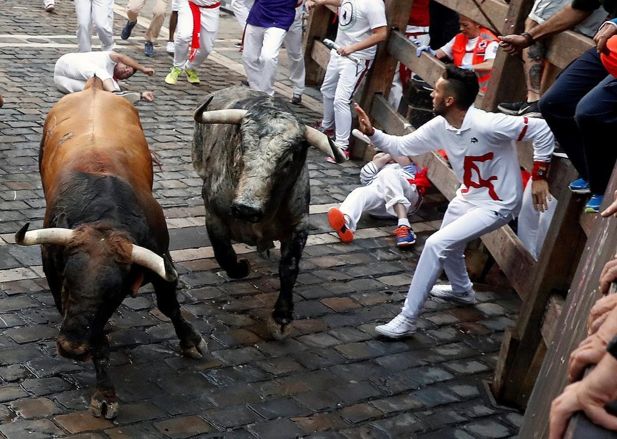 GRAF6263. PAMPLONA, 09/07/2018.- Los toros de la ganadería gaditana de Cebada Gago a su paso por la curva de Mercaderes durante el tercer encierro de los Sanfermines 2018 que ha tenido momentos de peligro por las caídas tanto de los astados como de los corredores, sin al parecer heridos por asta. Con el suelo seco, por primera vez en estos Sanfermines, la carrera ha resultado la más rápida hasta el momento, con 2 minutos y 33 segundos invertidos en completar todo el recorrido, y la menos concurrida, lo que ha posibilitado bonitas carreras. EFE/Villar López