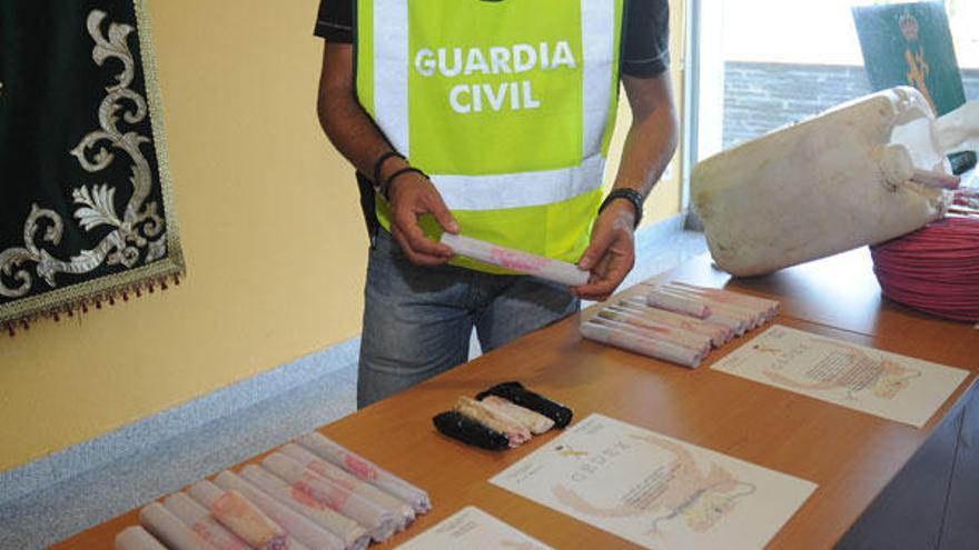 Un guardia civil delante de los explosivos incautados. En el recuadro, el cilindro donde los almacenaban.  // R. Vázquez