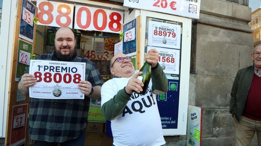 Juan Fernández, lotero de la Porta do Sol de Vigo, descorcha una botella de champán, ayer, a las puertas de la administración. |  // MARTA G. BREA