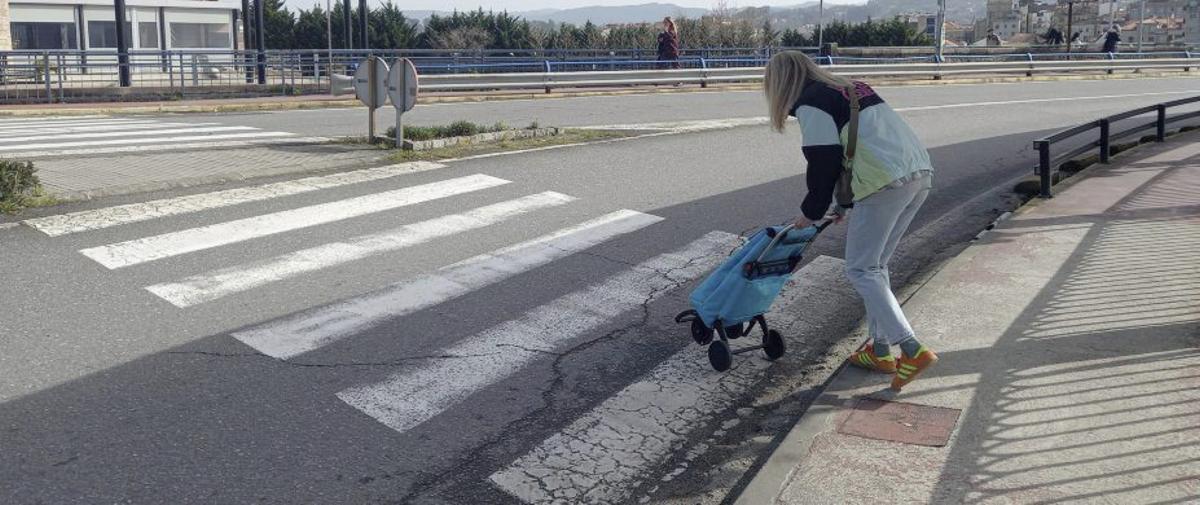 Una mujer pelea con el carrito para bajar una acera poco accesible. | GUSTAVO SANTOS