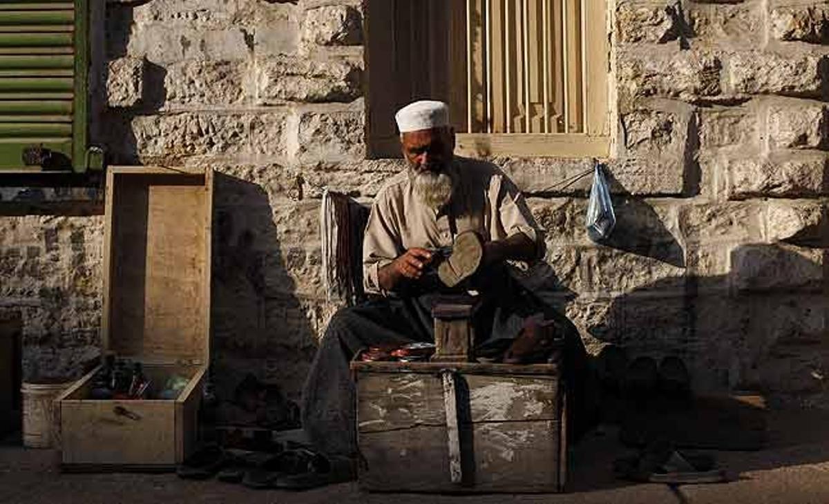 Ghaffar Khan enllustra un parell de sandàlies a la seva parada ambulant en una carretera a Karachi (Pakistan).