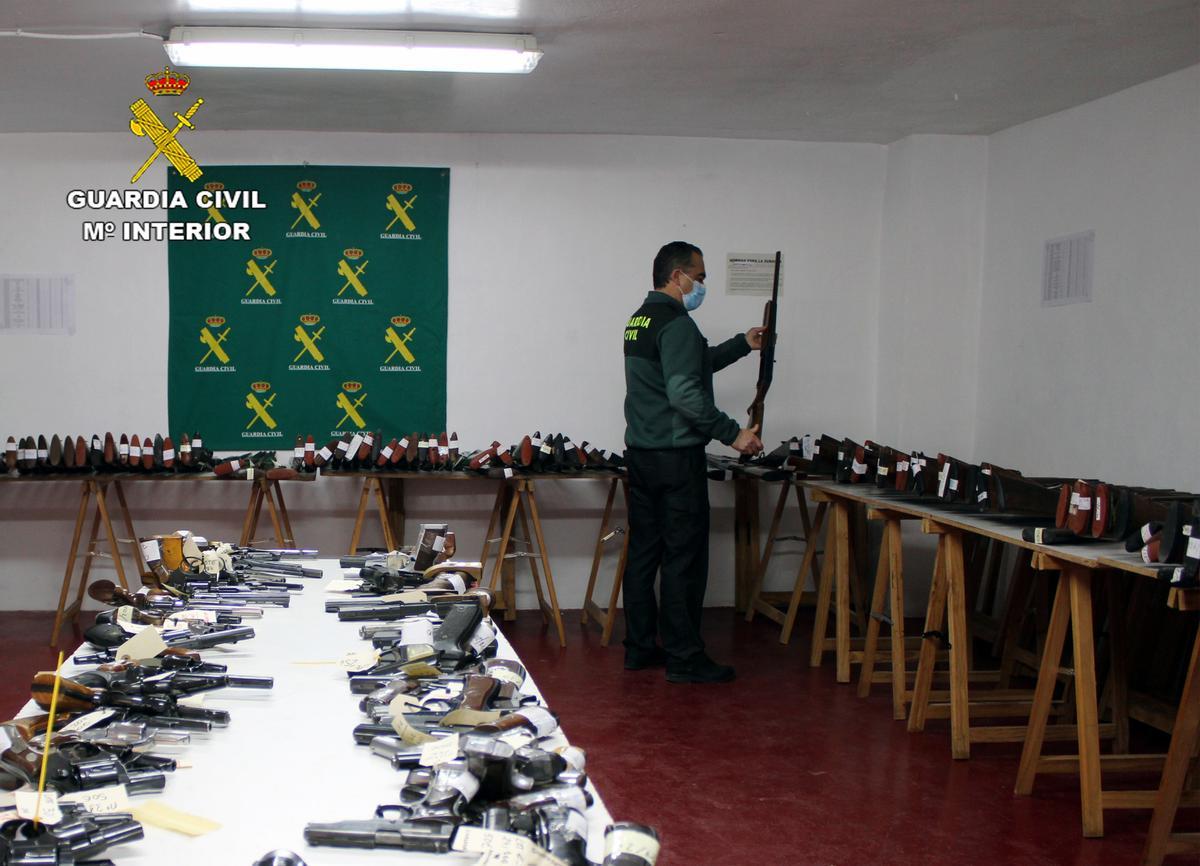 Un guardia civil revisando una escopeta del lote que será subastado en Murcia.