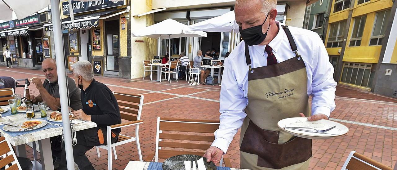 Un camarero coloca platos sobre una mesa en una terraza de la playa de Las Canteras de la capital grancanaria. | | ANDRÉS CRUZ