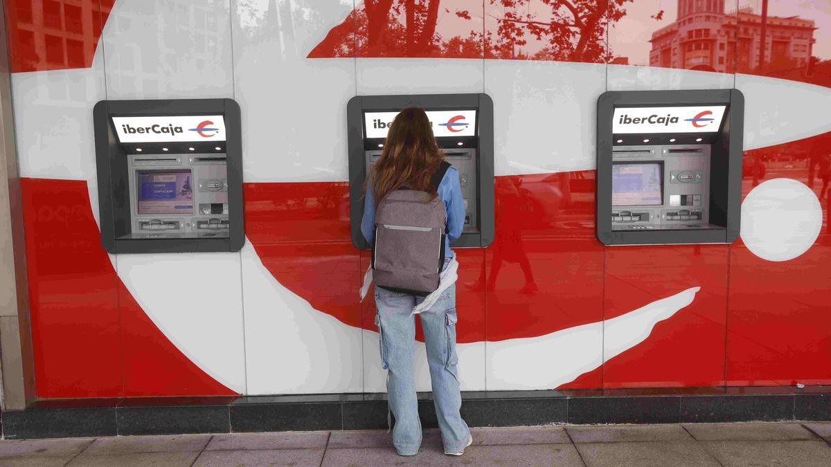 Una joven realiza una operación bancaria en una oficina en Zaragoza.